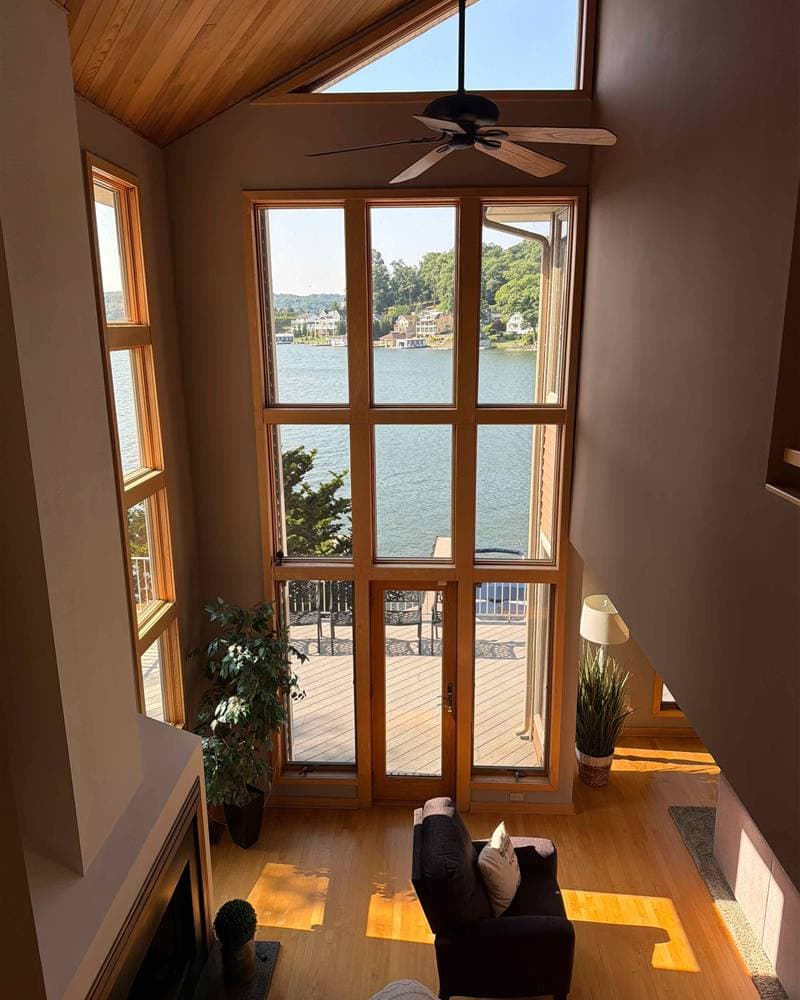A vaulted living room with a wall of windows overlooking a New Jersey lake, spotless after a YassClean visit.
