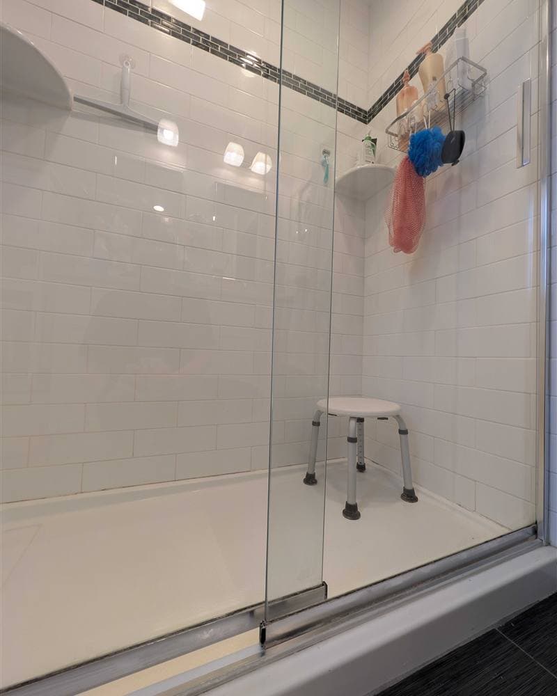 A spotless glass-enclosed shower with white subway tile, cleaned by a premium New Jersey house cleaning service.
