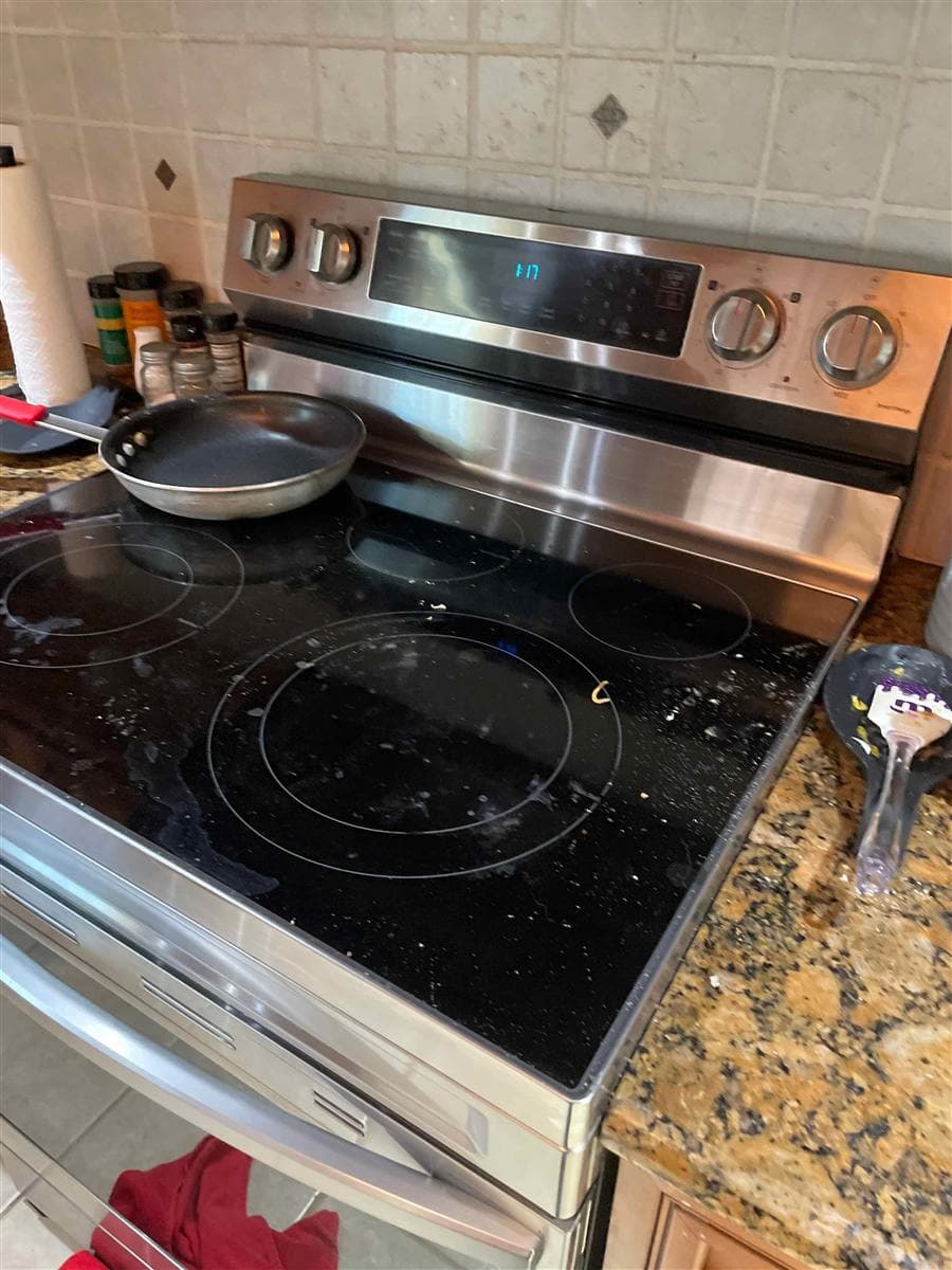Glass cooktop with food splatter and a used frying pan before cleaning in Branchville, NJ