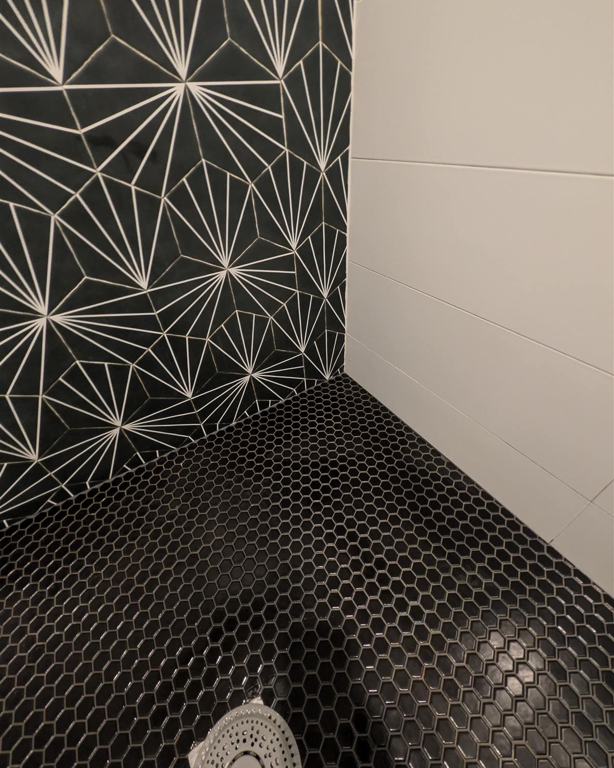 Cleaned shower with black hexagonal mosaic floor and patterned starburst tile wall in a Denville, NJ bathroom