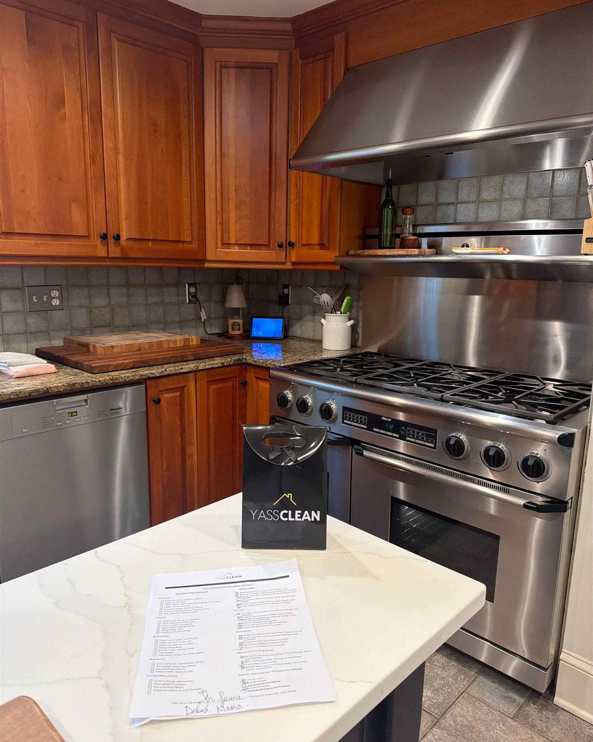 Cleaned kitchen with polished stainless steel range and hood, granite counters, and YassClean bag on the island in Mountain Lakes, NJ