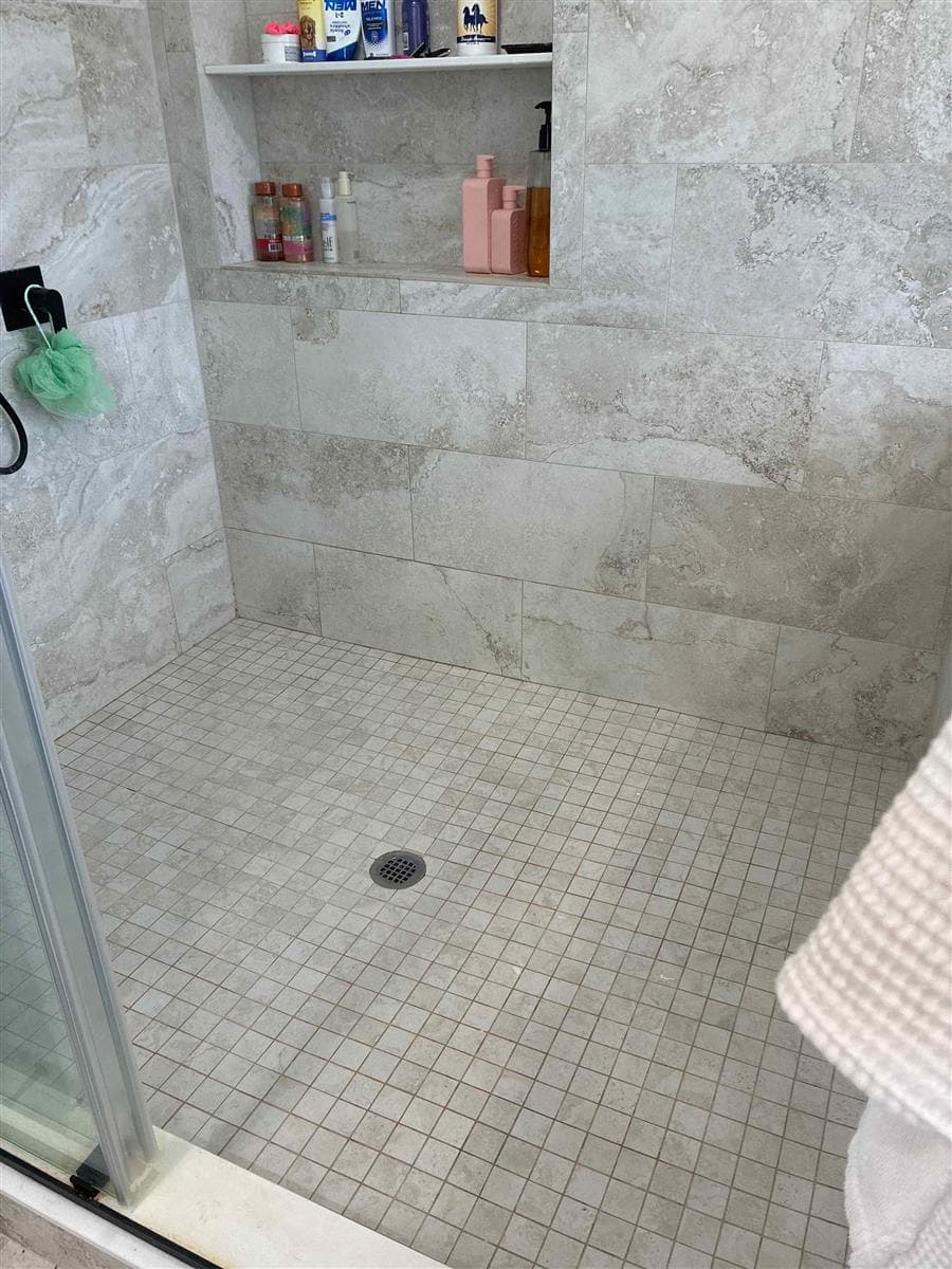 Tiled walk-in shower with soiled grout and floor before cleaning in Newton, NJ