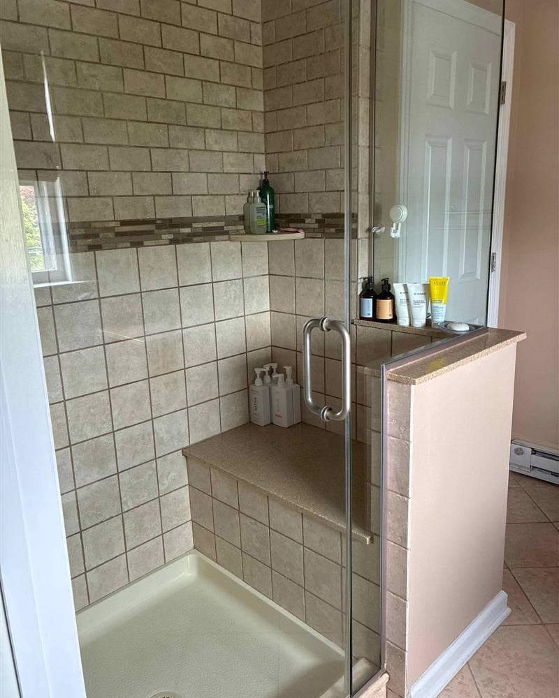 Cleaned tiled walk-in shower with glass door and built-in bench in a Sparta, NJ bathroom