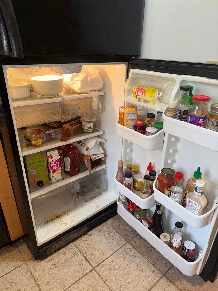 Refrigerator interior crowded with food and spills before cleaning in Sparta, NJ