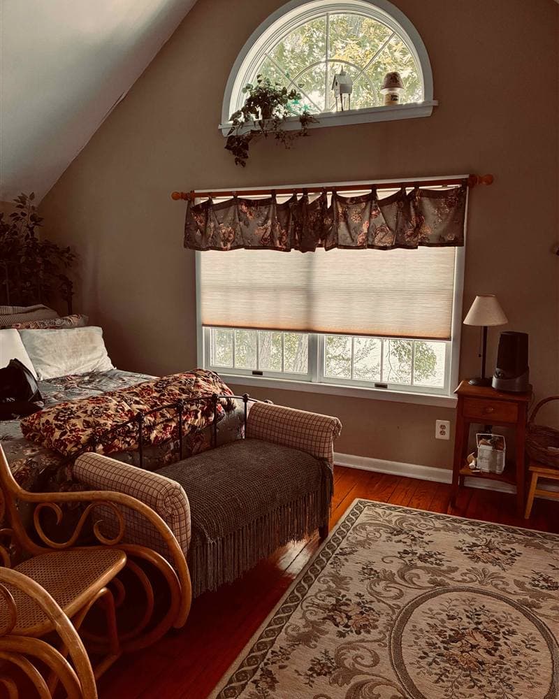 Bedroom with a neatly made bed, rocking chair, and arched window after a cleaning in Branchville, NJ