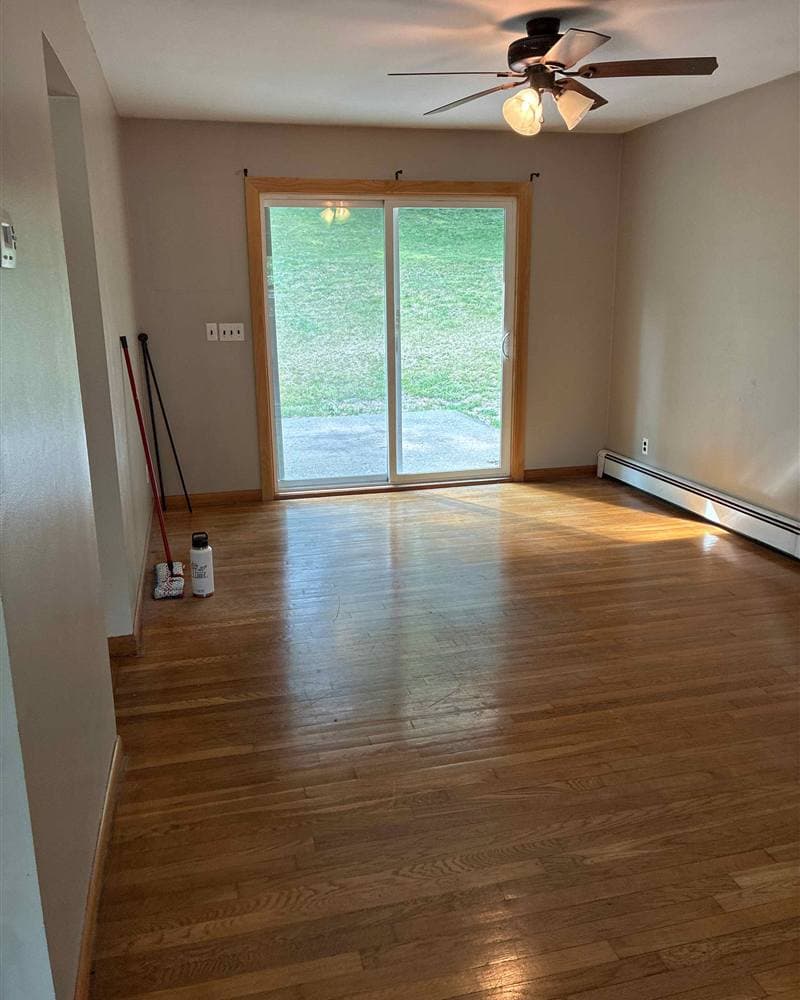 Polished hardwood floors in an empty living room with sliding glass door after a move-out clean in Newton, NJ